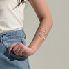Person wearing a silver bracelet on a plain background