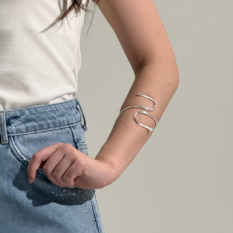 Person wearing a silver bracelet on a plain background