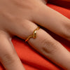 Gold ring on a finger against an orange background