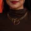 Close-up of a person wearing a gold necklace with a dark background