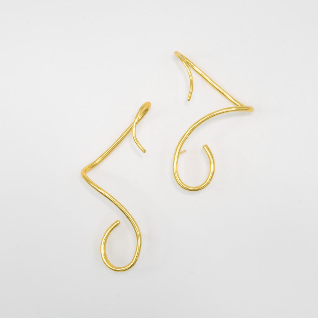 Gold earcuffs on a light gray background