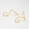 Gold wire earcuffs on a light gray background