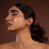 Woman wearing silver earcuff against a brown background
