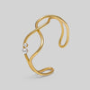 Gold bracelet with two pearls on a light gray background
