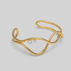 Gold bracelet with two small pearls on a light gray background