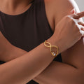 Woman wearing a gold bracelet with a neutral background