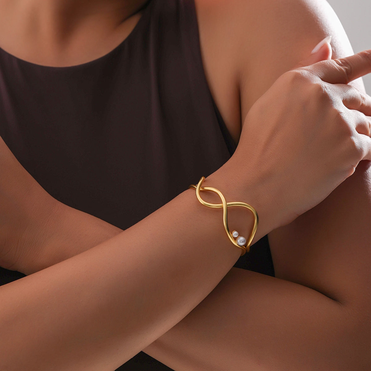 Woman wearing a gold bracelet with a neutral background