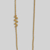 Gold necklace on a light gray background