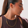 Woman wearing a gold necklace against a neutral background