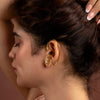 Woman wearing a gold earcuff with a blurred background