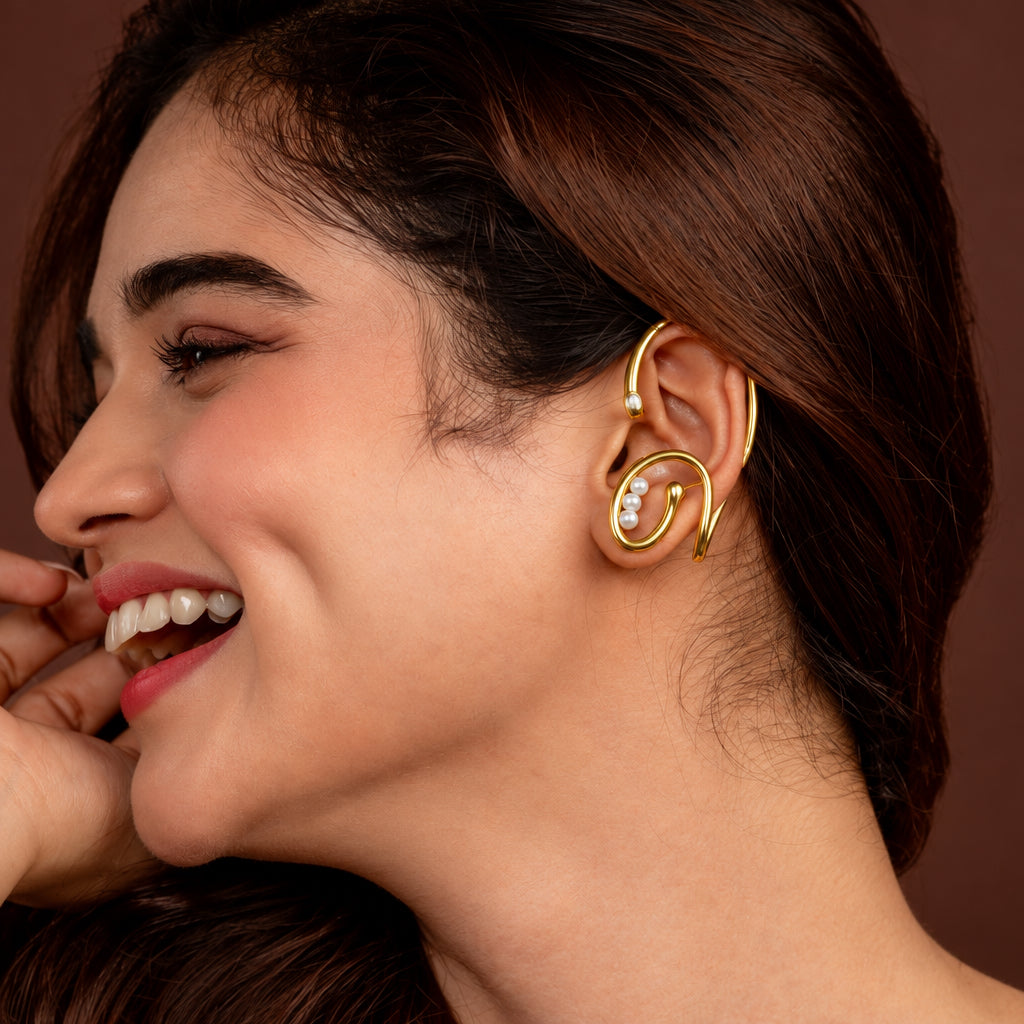 Woman in a gold earcuffs posing against a brown background