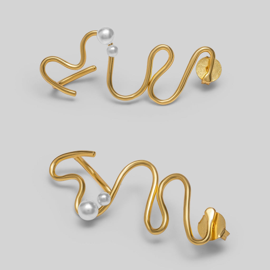 Gold wire earrings with pearls on a light gray background