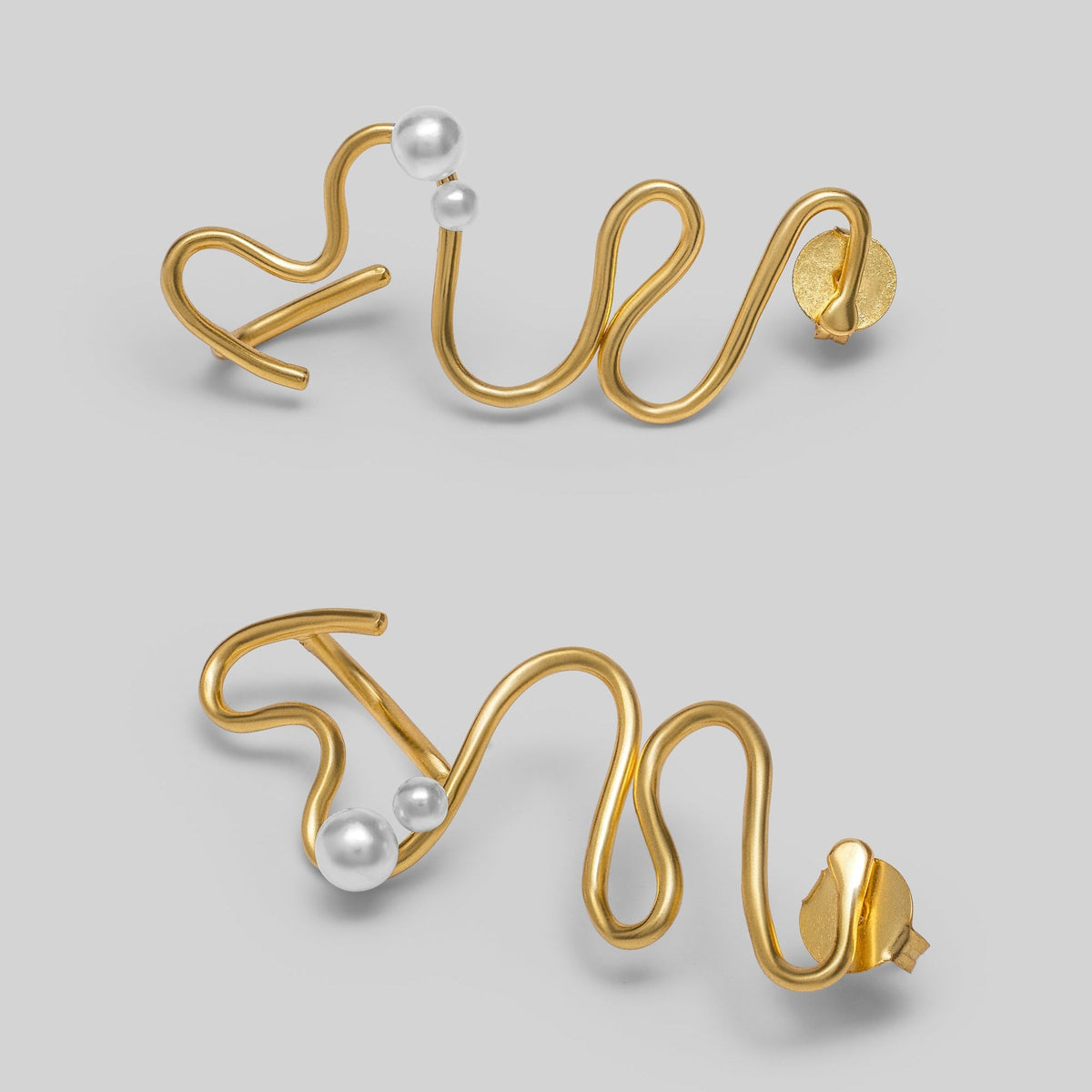 Gold wire earrings with pearls on a light gray background