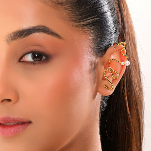Close-up of a woman wearing a gold ear cuff with a pearl accent.