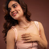Woman wearing a pink dress with a gold necklace on brown background