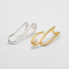 Gold and silver open cuff earrings with pearls on a light gray background