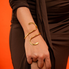 Gold bracelet on a wrist against an orange background