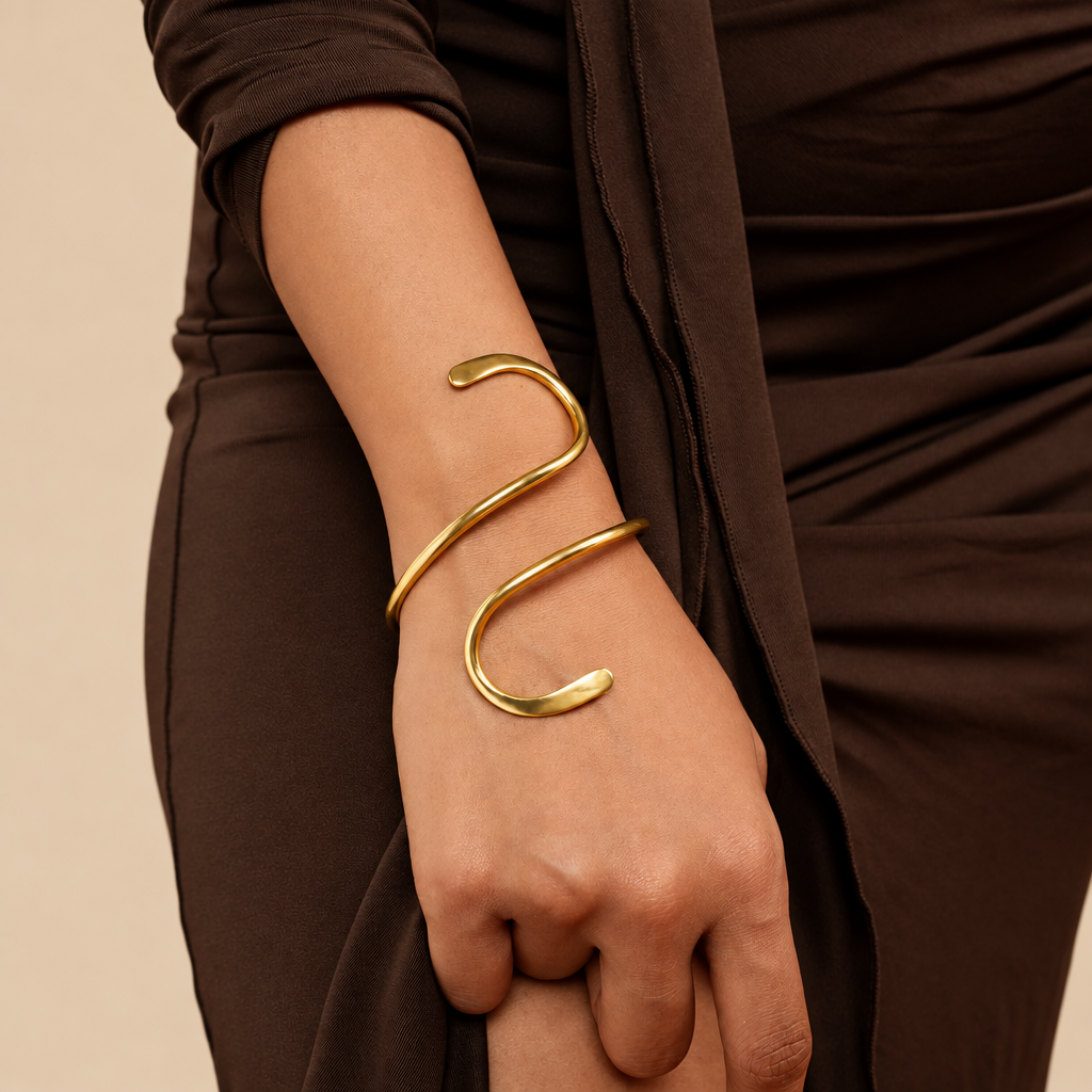 Gold bracelet on a wrist against an orange background