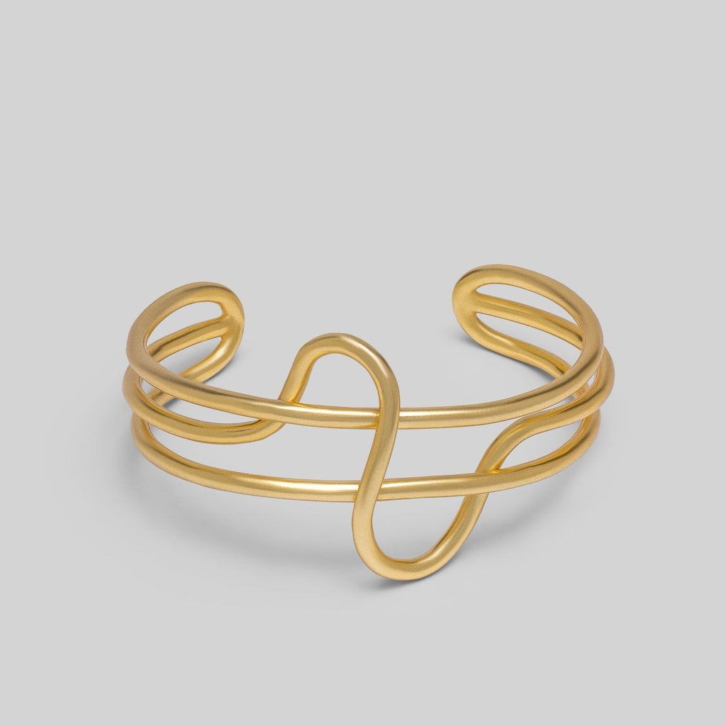 Gold wire bracelet on a light gray background