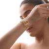 Woman wearing a gold bracelet on a plain background