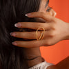 Woman wearing a gold ring on her finger with an orange background