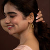 Woman wearing gold hoop earrings with a blurred background