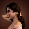 Woman wearing gold hoop earrings against a brown background