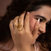 Woman wearing a gold ring with a unique design, close-up shot.