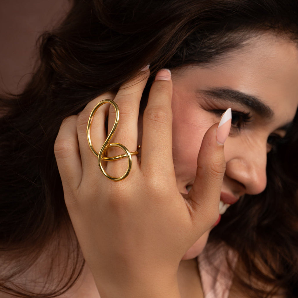 Woman wearing a gold ring with a unique design, close-up shot.