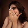 Woman wearing a silver ring on her finger against a brown background