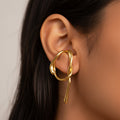 Gold earring worn by a person with dark hair.