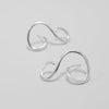 Pair of silver ear cuffs on a light gray background