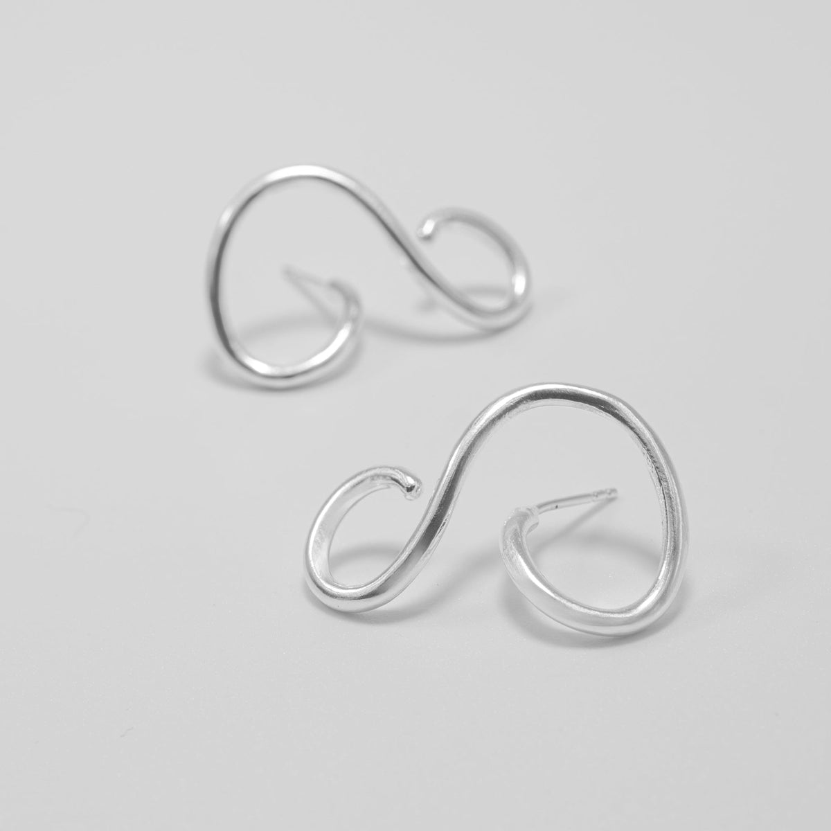 Pair of silver ear cuffs on a light gray background