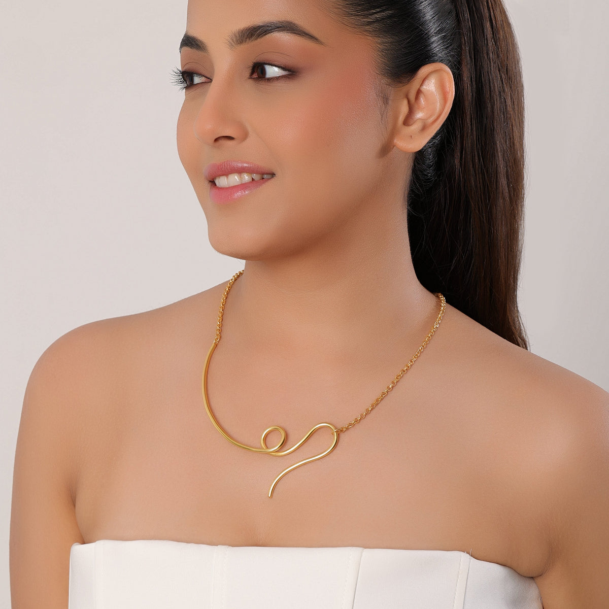 Woman wearing a gold necklace against a plain background