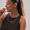 Woman wearing a silver necklace against a neutral background