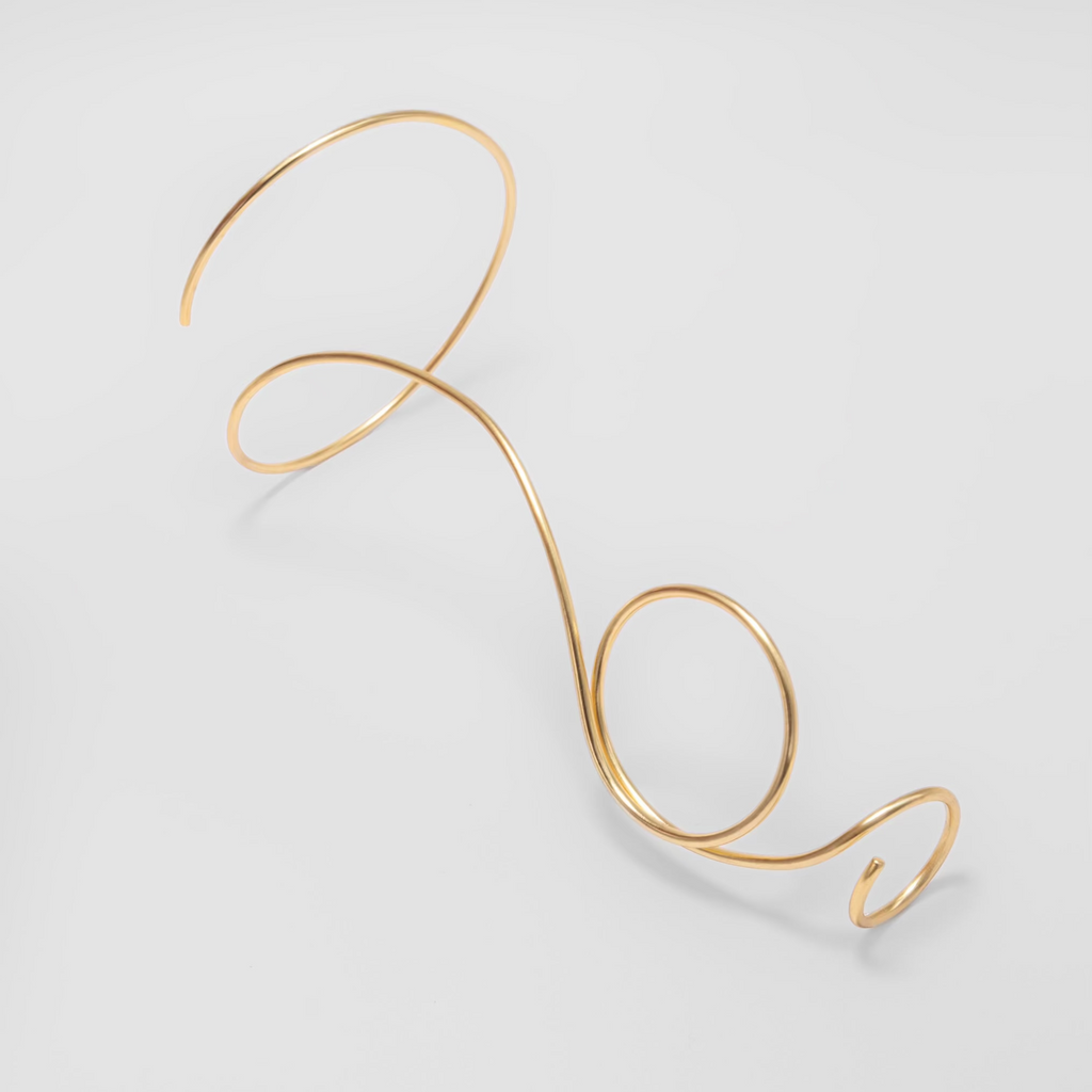 Gold wire bracelet on a light gray background
