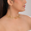 Woman wearing a gold choker necklace against a neutral background