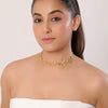 Woman wearing a gold choker necklace against a plain background