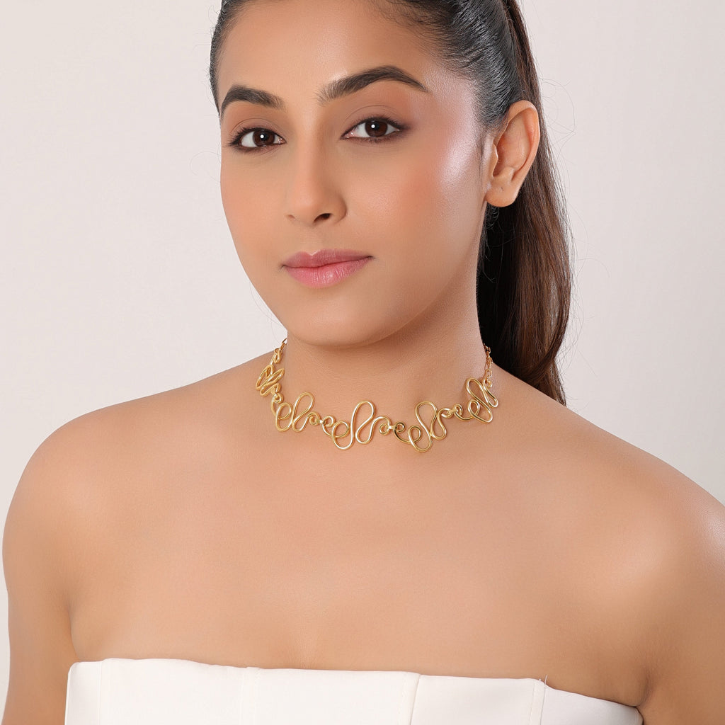 Woman wearing a gold choker necklace against a plain background