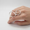 Silver ring shaped like infinity on a hand with white background
