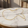 Gold necklace with a single pearl on a white background