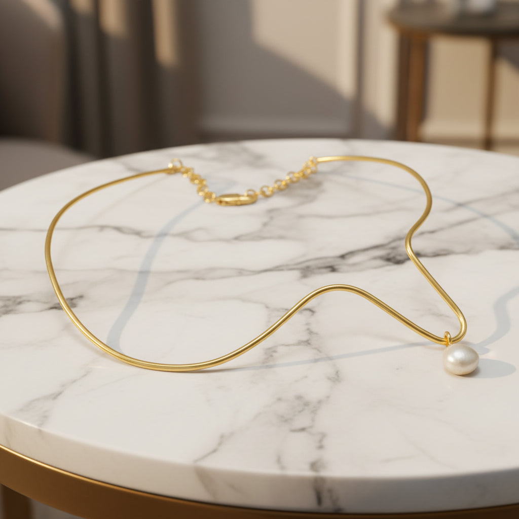 Gold necklace with a single pearl on a white background