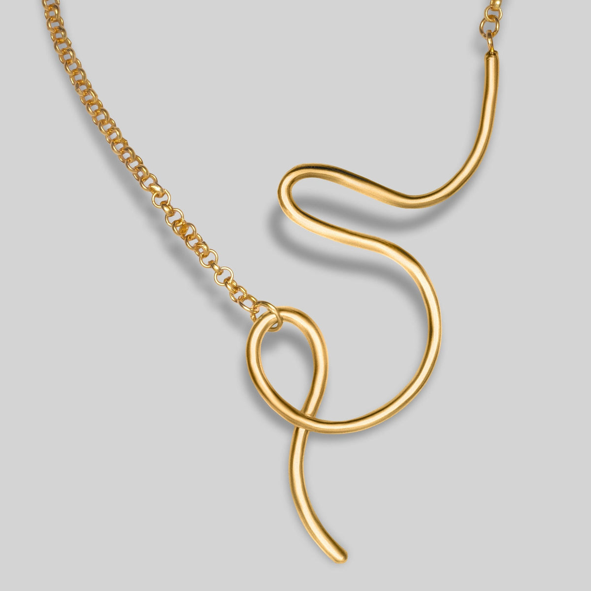 Gold necklace with a unique pendant on a light gray background
