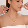 Woman wearing a gold necklace with a plain background