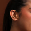 Gold ear cuff worn by a person against a brown background