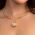 Gold necklace with a pink gemstone worn by a person