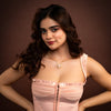 Woman wearing a pink dress and necklace against a brown background