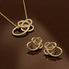 Gold necklace and earrings on a reflective brown surface