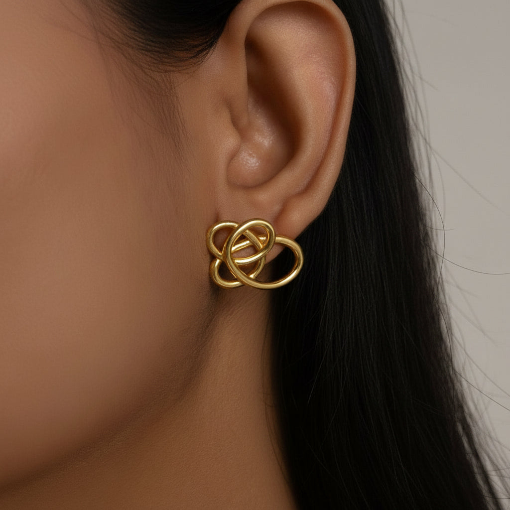 Gold earring worn by a person with dark hair and skin.