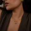 Woman wearing gold earrings and necklace against a dark background
